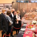 grupka osób przy stole z XIX w. podczas wystawy "Zabytkowe sztućce i zastawy stołowe" w hali Lejniczej